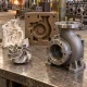 Investment cast small steel component beside a larger sand cast housing and foundry mold samples